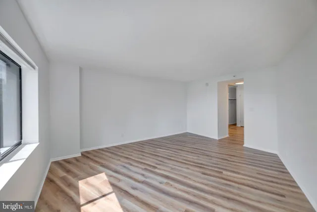a view of an empty room with wooden floor and a window