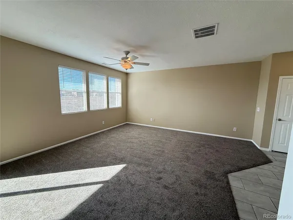 an empty room with windows and ceiling fan