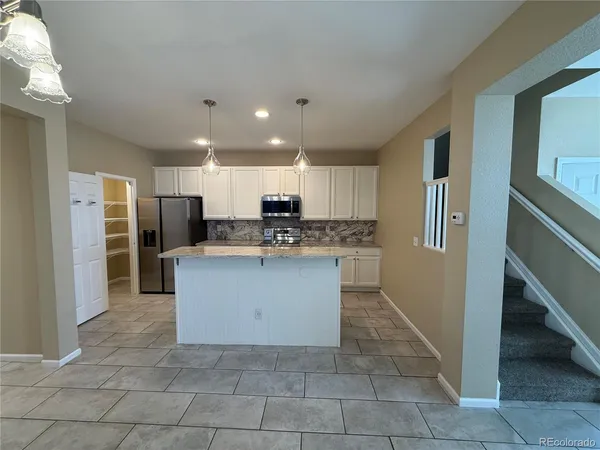 a large kitchen with stainless steel appliances kitchen island granite countertop a refrigerator and a sink