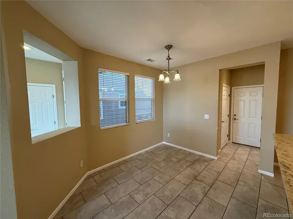 a view of an empty room with window and chandelier fan