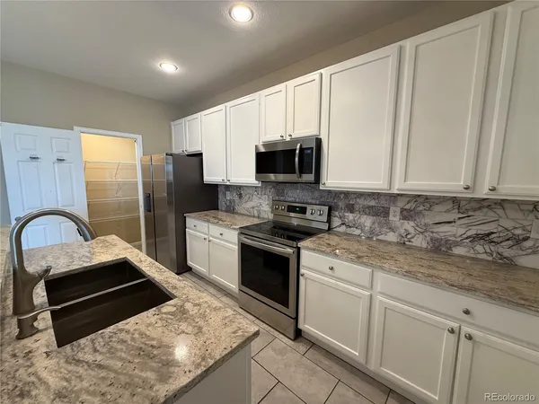 a kitchen with stainless steel appliances kitchen island granite countertop a stove a sink and a refrigerator