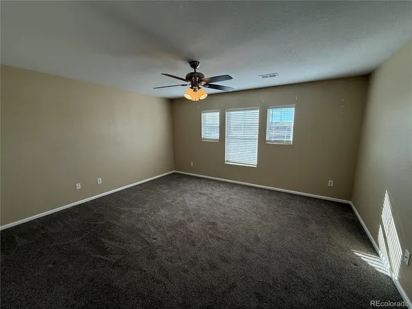 an empty room with windows and fan