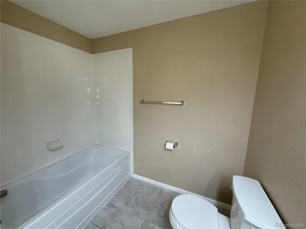 a bathroom with a granite countertop toilet and a bathtub