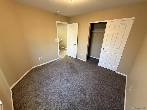 an empty room with a ceiling fan and carpet