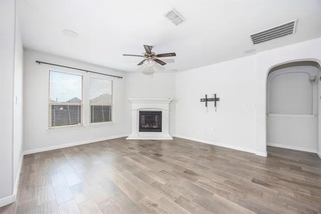 a view of an empty room with a window and wooden floor