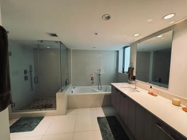 a bathroom with a double vanity sink mirror and bathtub