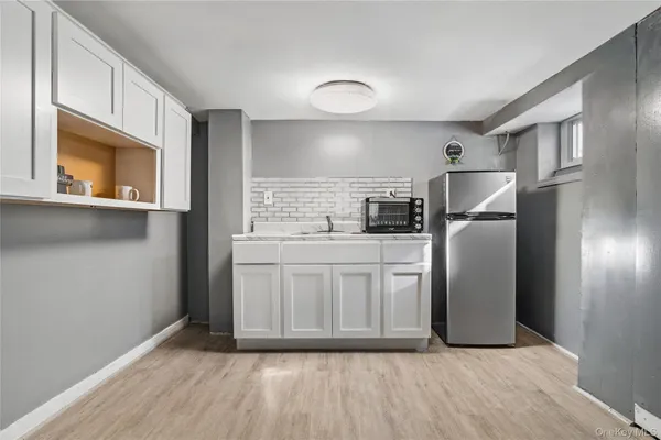 a kitchen with stainless steel appliances granite countertop a refrigerator a stove a sink and white cabinets with wooden floor