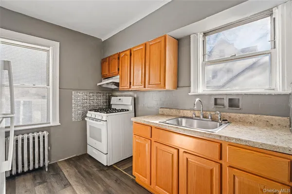 a kitchen with stainless steel appliances granite countertop a sink a stove a refrigerator wooden floor and a large window