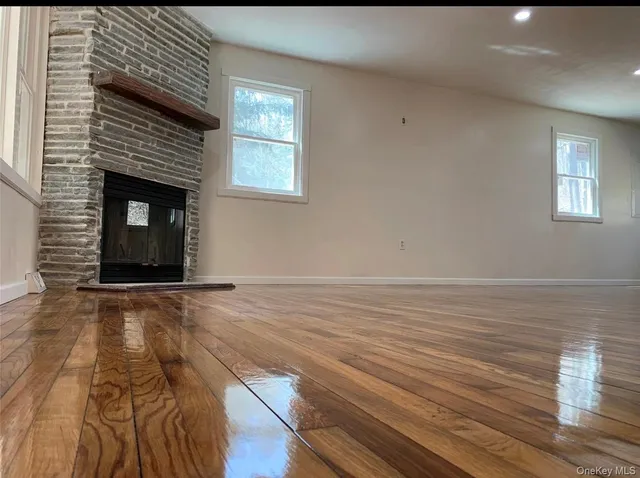 a view of an empty room with wooden floor and a fireplace