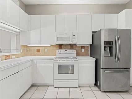 a kitchen with white cabinets stainless steel appliances and white appliances