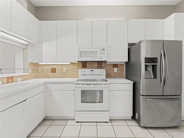 a kitchen with white cabinets stainless steel appliances and white appliances