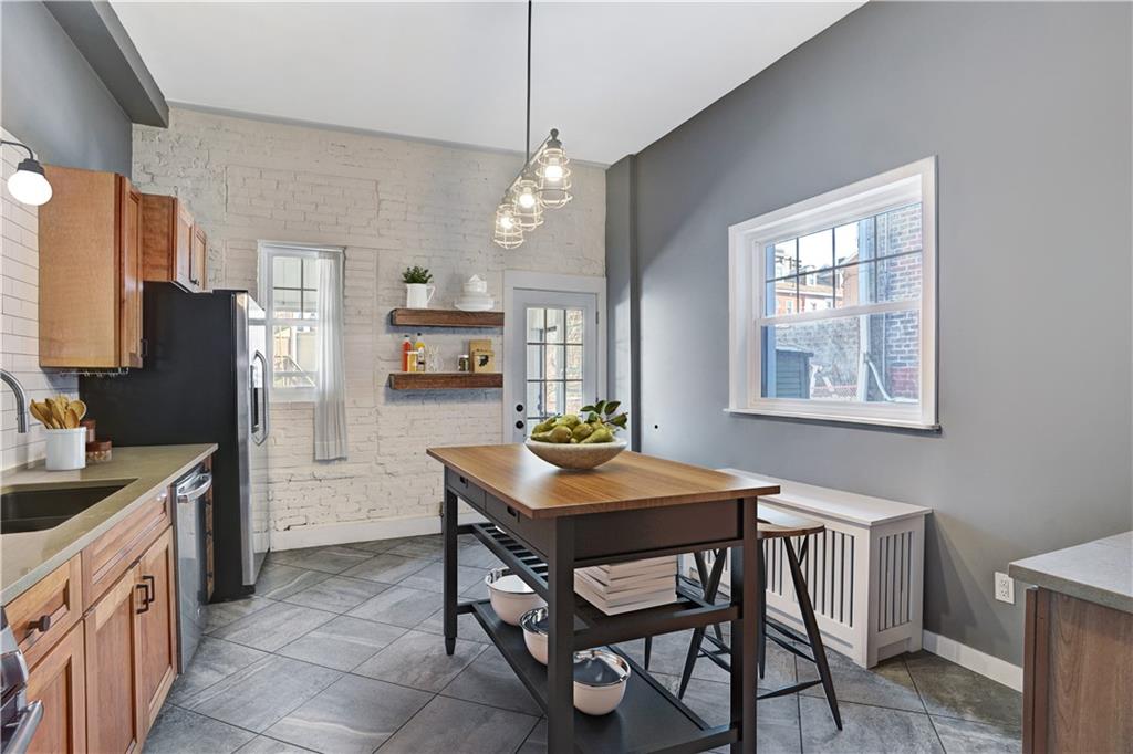 315 Main Street Pittsburgh, PA 15201 - Photo 7 of 23 a kitchen with stainless steel appliances granite countertop a stove a refrigerator a sink dishwasher a dining table and chairs with wooden floor