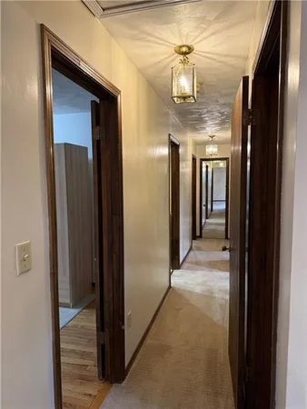 a view of a hallway with wooden floor and chandelier