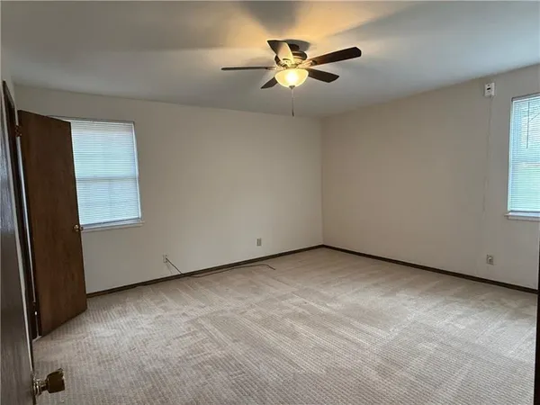 an empty room with windows and fan