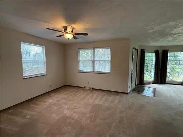 an empty room with windows and chandelier fan
