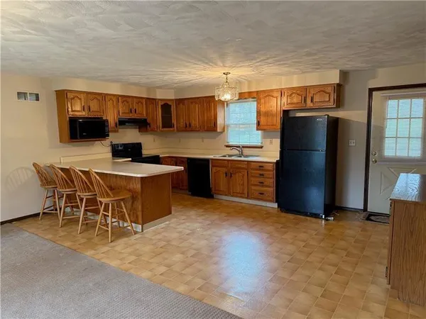a kitchen with stainless steel appliances granite countertop a table chairs and a refrigerator