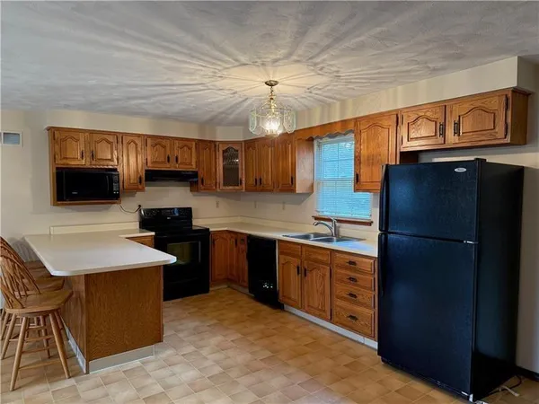 a kitchen with stainless steel appliances granite countertop a refrigerator a sink dishwasher a stove and white countertops with wooden floor