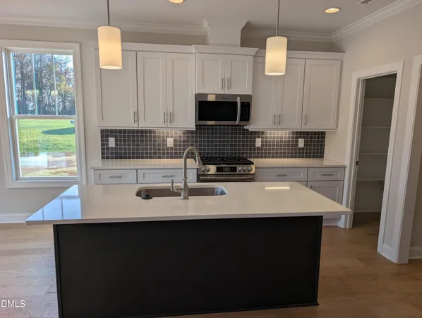 a kitchen with a sink a microwave a stove and white cabinets