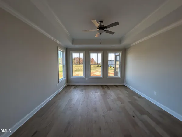 a view of an empty room with a window and wooden floor