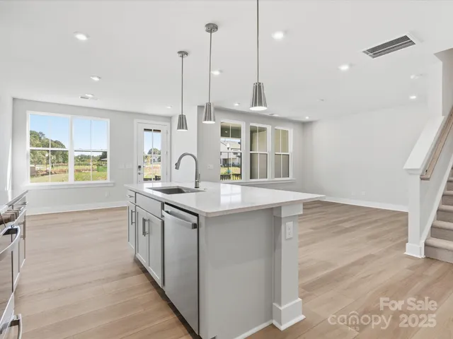 a kitchen with stainless steel appliances granite countertop a sink a stove and a wooden floor
