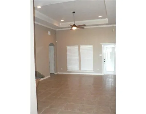 a view of an empty room with chandelier fan