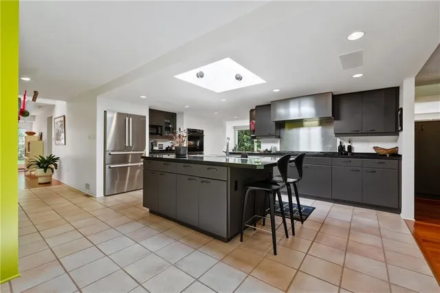 a kitchen with stainless steel appliances kitchen island granite countertop a refrigerator and a sink