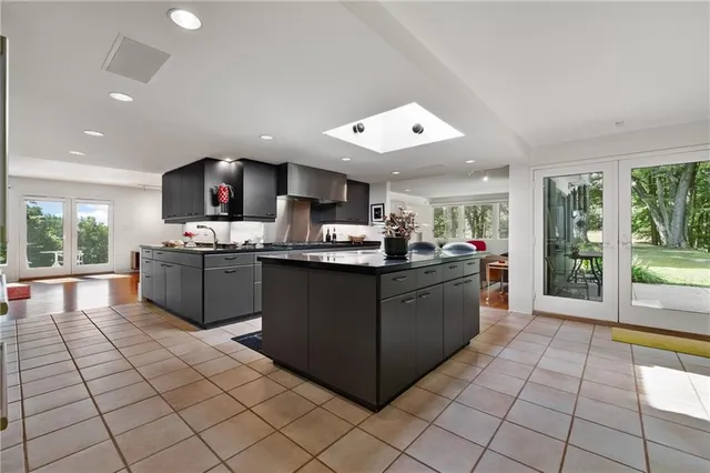 a kitchen with stainless steel appliances granite countertop a stove top oven a sink a counter top space cabinets and a view of living room