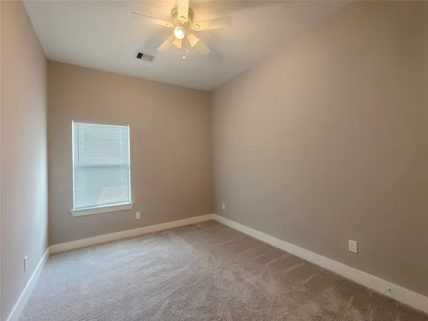 an empty room with a chandelier fan and a window