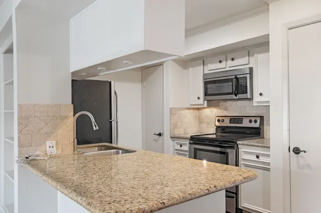 a kitchen with granite countertop a stove cabinets and microwave