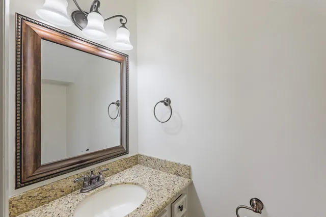 a bathroom with a granite countertop sink and a mirror