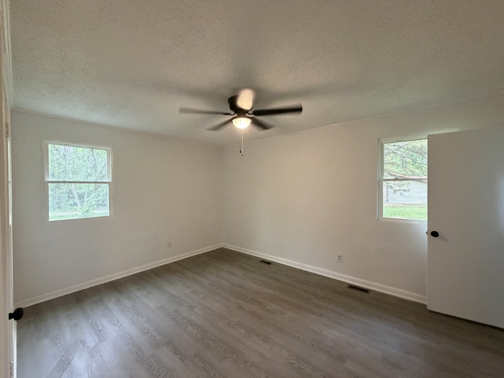 920 Damron Loop Counce, TN 38326 - Photo 9 of 14 an empty room with wooden floor ceiling fan and windows