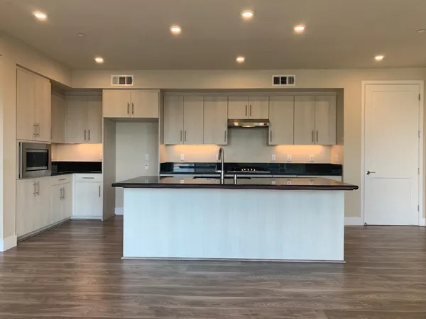 a large kitchen with stainless steel appliances a large counter top a stove and a refrigerator