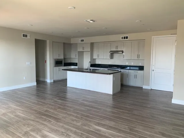 a kitchen with stainless steel appliances granite countertop a stove top oven a sink and white cabinets