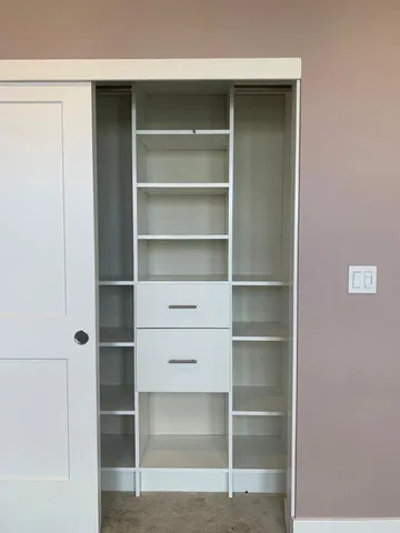 a view of walk in closet with empty racks