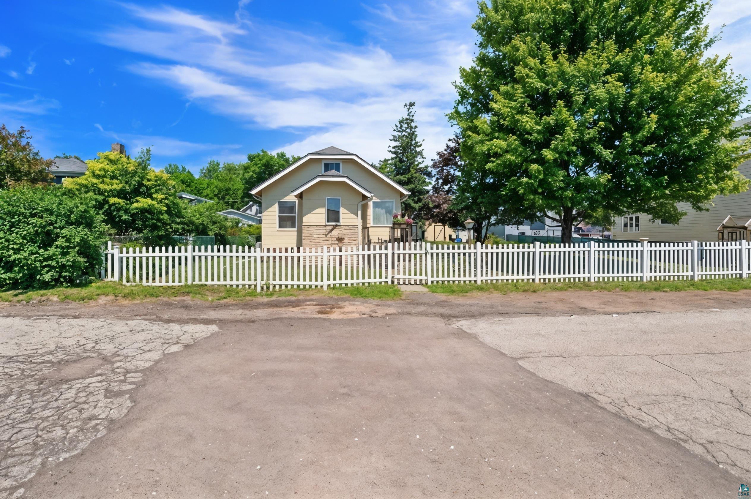 3209 Chestnut Street Duluth, MN 55806 - Photo 2 of 28 Picket fenced property featuring a beige exterior with stone accents, gable roofline, and mature landscaping