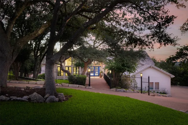 a front view of a house with garden and trees