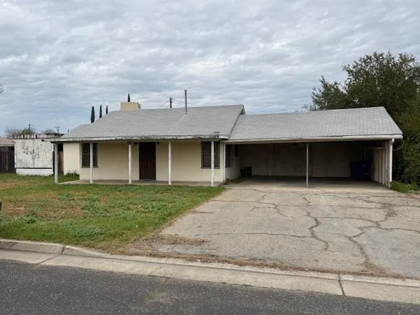 a front view of a house with a garden and trees