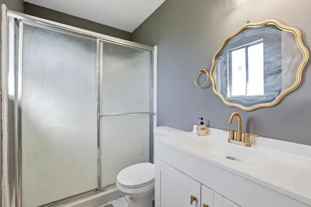 a bathroom with a toilet sink vanity and mirror