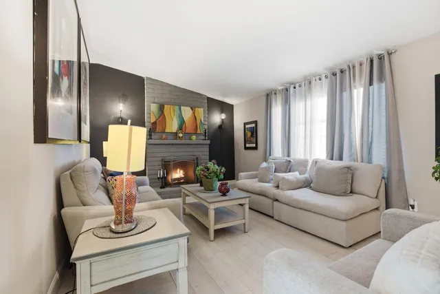 a living room with furniture fireplace and a large window