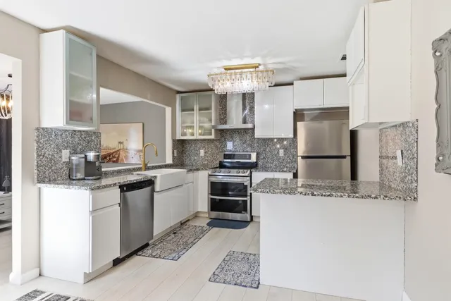 a kitchen with stainless steel appliances granite countertop a refrigerator a stove a sink a microwave and island