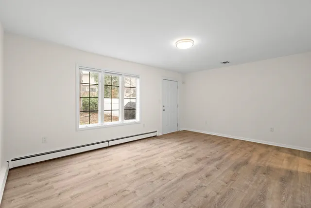 an empty room with wooden floor and windows