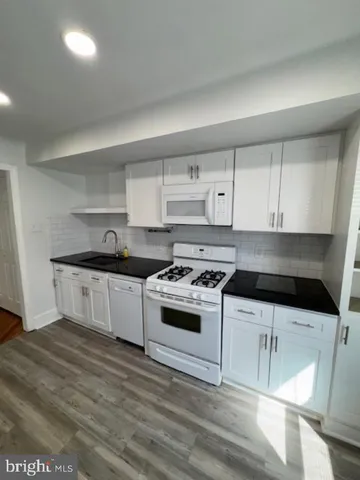 a kitchen with granite countertop a stove and white cabinets