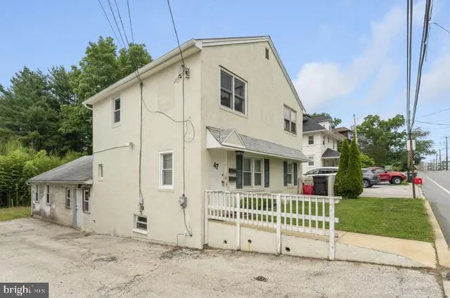 a view of a white house with a yard and plants