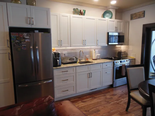 a kitchen with granite countertop a refrigerator stove microwave and cabinets