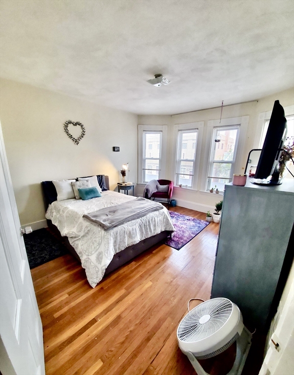 40 Forest Street, Unit 3 Boston, MA 02119 - Photo 18 of 20 a bedroom with a bed and wooden floor