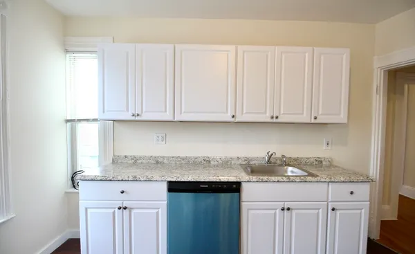 a kitchen with granite countertop white cabinets and a sink