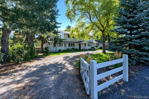 a view of a wooden house with large trees and wooden fence