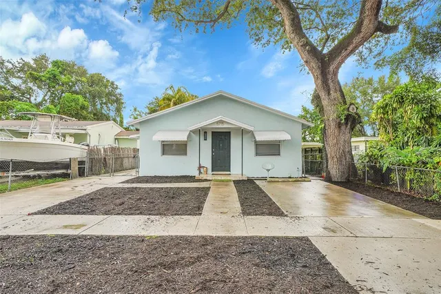 a view of a house with a yard and large tree
