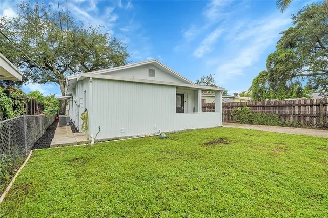 a backyard of a house with plants and large tree