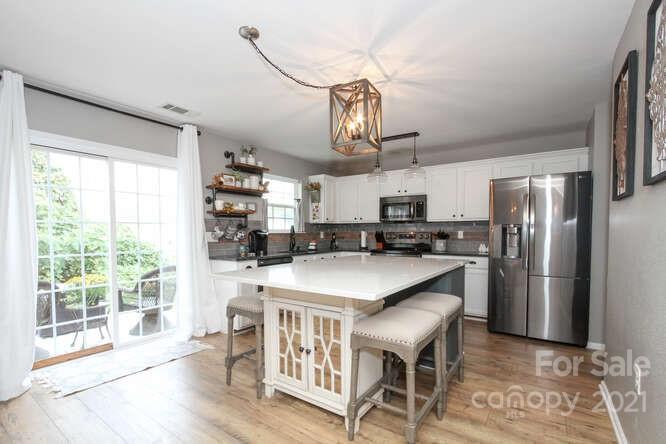1431 River Run Road Lowell, NC 28098 - Photo 11 of 26 a kitchen with stainless steel appliances granite countertop a table chairs refrigerator and microwave